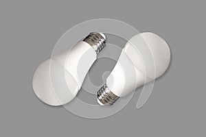 Two led bulb lights and energy-saving lamps on table on gray background