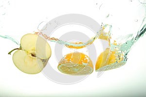 Two, lemon and apple slices splash of water on white background