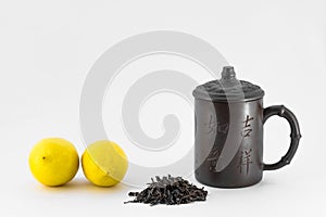 Two lemons, chinese mug and dry tea on white background