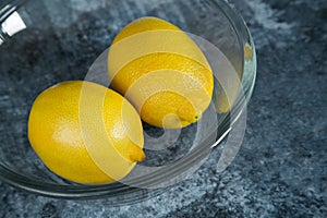 Two lemons in a glass plate on a marble background. Cold medicine.