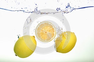 Two lemons and lemon slice spash in water on white background photo