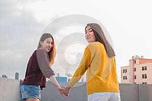 Two lesbian couple holding hand and walking together on rooftop