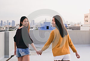 Two lesbian couple holding hand and walking together on rooftop