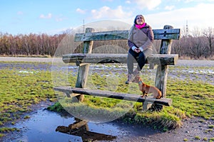 Two-level wooden bench with a senior adult woman next to her dog taking a break