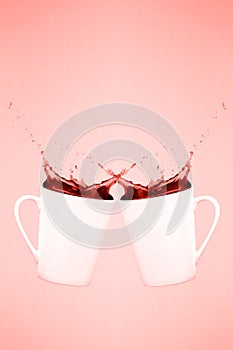 Two levitating coffee mugs with splashes. Coffee concept. Minimal art trend. Solid pink background . Living coral theme - color of