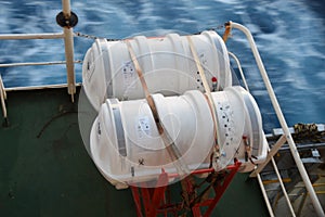 Two Liferafts secured with white straps in the red cradle on the cargo container ship