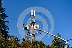 Two linemen working on a wireless communications radio and antenna installation using a bucket truck photo