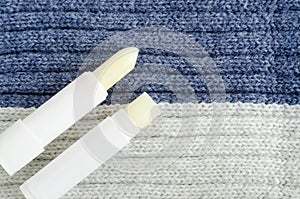 Two lip balms on the knitted background. Winter lip care sticks with beeswax, honey, panthenol and shea butter. Copy space. photo