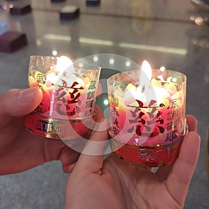 Two lit chinese praying candle for Chinese new year celebration held by couple lovers