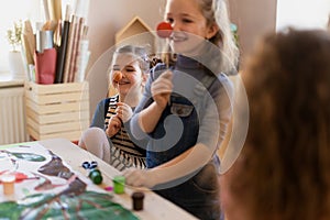 Two litlle girlss working on project, smiling and having fun during creative art and craft class at school.