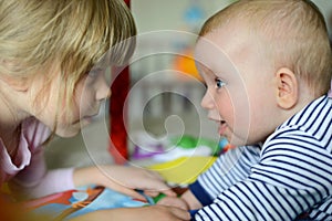 Two little adorable Caucasian sisters look at each other. They are happy and smiling.