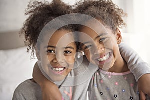 Two little african american girls on bed at home