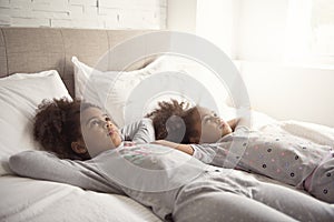 Two little african american girls on bed at home