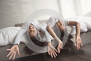 Two little african american girls on bed at home