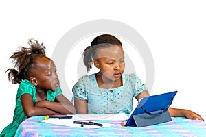 Two little african girls watching tablet at table