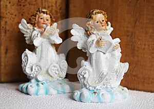 Two little angel stay on a wooden background