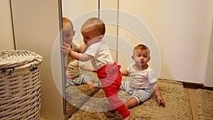 Two little babies, having fun with the mirror. Twin girl sisters, playing