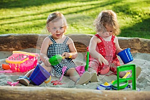 The two little baby girls playing toys in sand