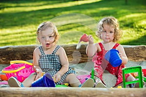 The two little baby girls playing toys in sand