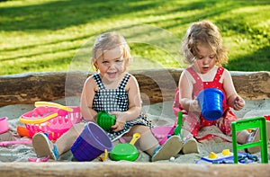 The two little baby girls playing toys in sand