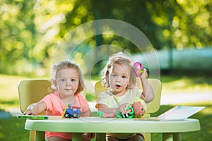 The two little baby girls playing toys in sand