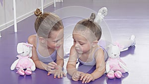 Two little ballerinas lying on the floor at ballet school resting after practicing