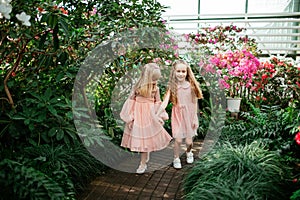 Two little beautiful sisters are walking and having fun in azaleas park