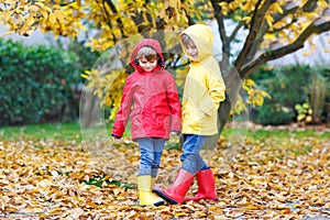 Two little best friends and kids boys autumn park in colorful clothes. Happy siblings children having fun in red and