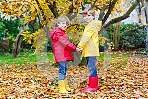 Two little best friends and kids boys autumn park in colorful clothes. Happy siblings children having fun in red and