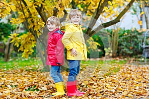 Two little best friends and kids boys autumn park in colorful clothes.