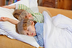 Two little blond sibling boys sleeping in bed