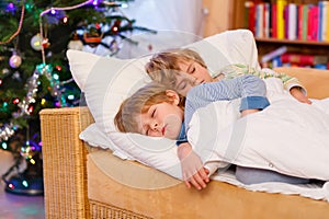 Two little blond sibling boys sleeping in bed on Christmas