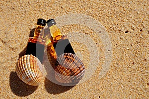 Two little bottles whiskey lie on the sand. Alcohol top view from above