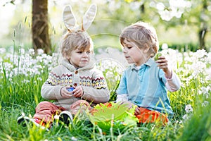 Two little boy friends in Easter bunny ears during egg hunt