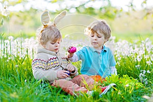 Two little boy friends in Easter bunny ears during egg hunt