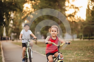 Two little boy and girl cyclists riding their bikes and enjoy having fun. Kid outdoors sport summer activity