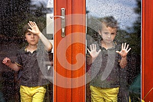 Two little boy, wearing same clothes looking through a big glass