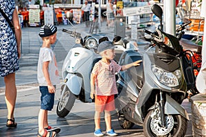 Two little boys admiring parked scooters in the resort town street