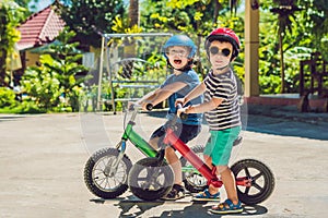 Two little boys children having fun on Balance Bike on a country tropical road