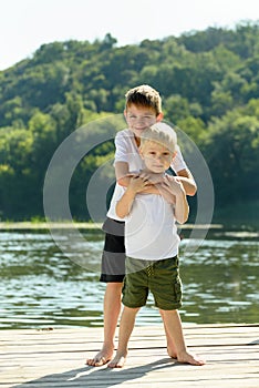 Two little boys are embracing on the bank of the river. Concept of friendship and fraternity