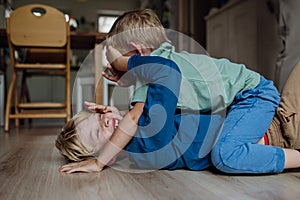 Two little boys fighting on the floor, brothers having fun at home. Concept of sibling relationship and brotherly love.