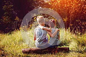 Two little boys friends hug each other in summer sunny day. Brother love. Concept friendship. Back view