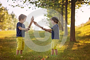 Two little boys, holding swords, glaring with a mad face at each