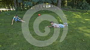 Two little boys lie on the grass, fooling around, playing, ball, park, summer, joy, positive