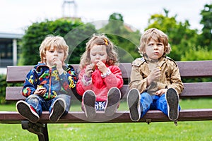 Two little boys and one girl eating chocolate