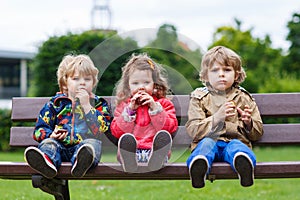 Two little boys and one girl eating chocolate