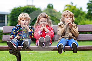 Two little boys and one girl eating chocolate