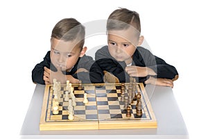 Two little boys play chess.