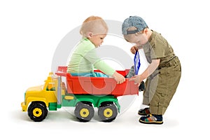 Two little boys play with toy truck