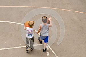 Two little boys playing on a basketball court